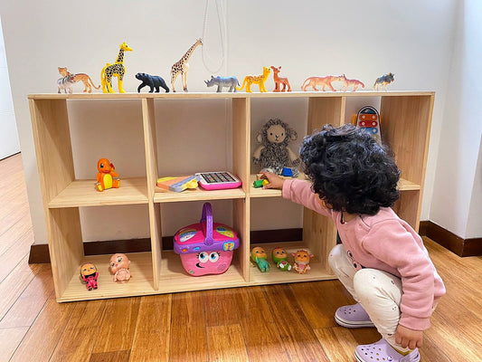 Niña guardando sus juguetes en una habitación Montessori